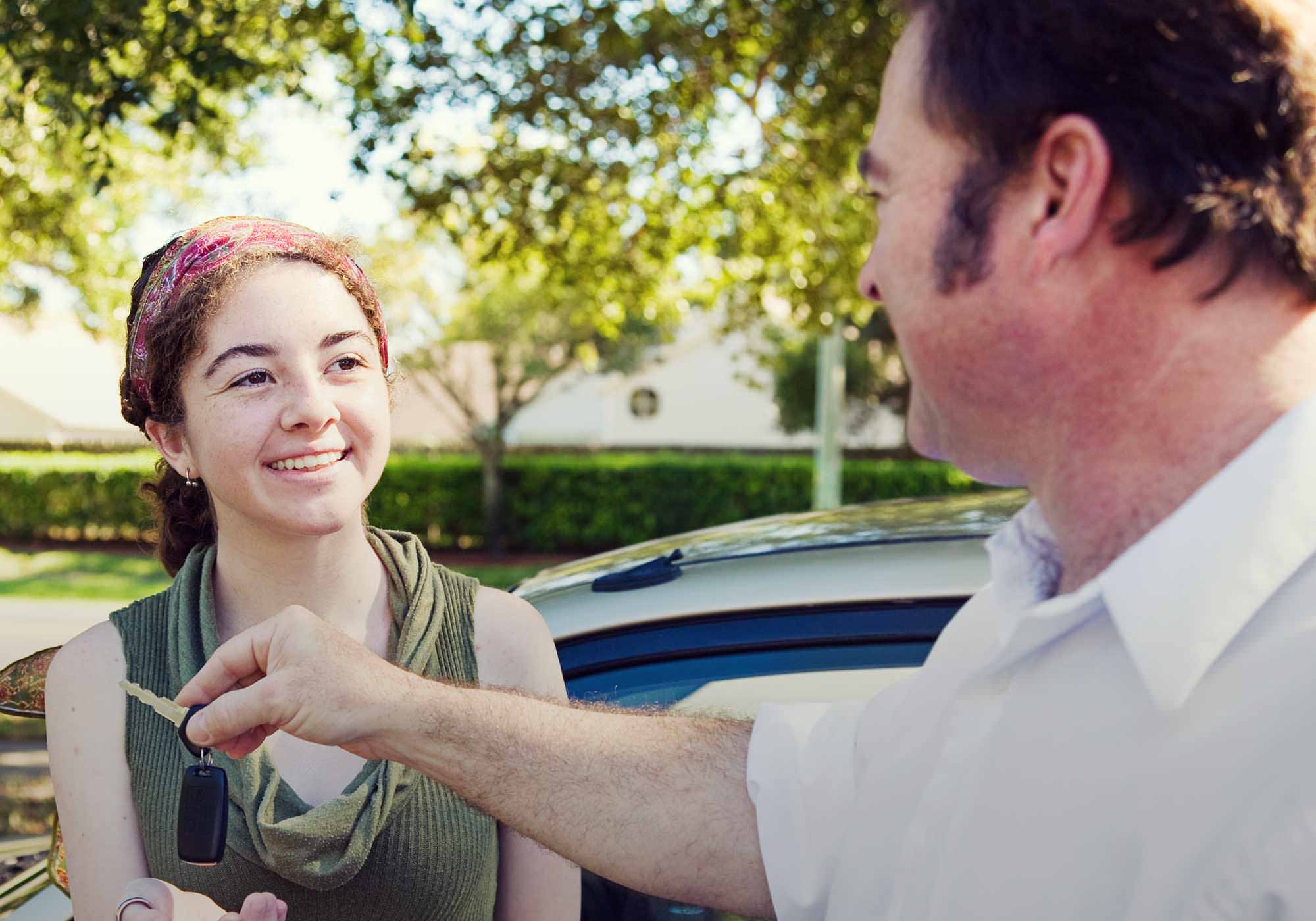 parent handing over car key to teenager